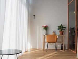 Praktijkruimte, 15 m2 Zitje met houten meubels Zalmroze stalen wand Houten vloer